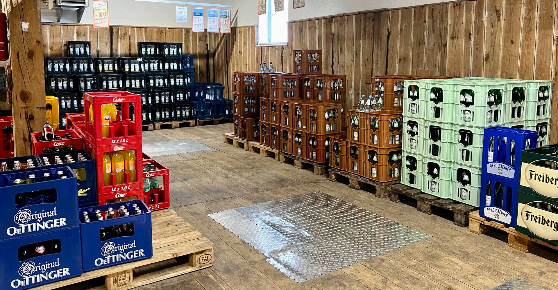 Ein Getränkelager mit verschiedenen bunten Getränkekisten auf Holzpaletten in einem Holzwandraum.